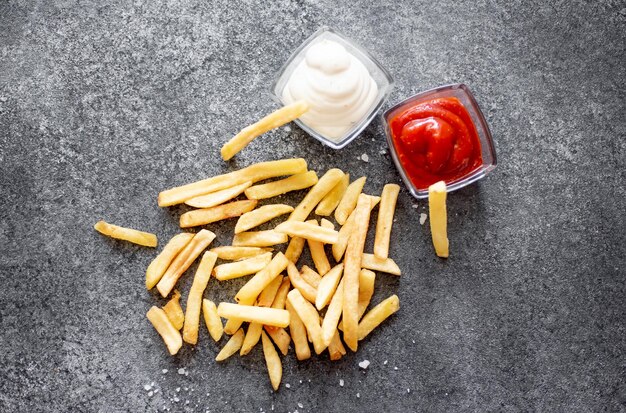 french fries with different sauces on a stone background