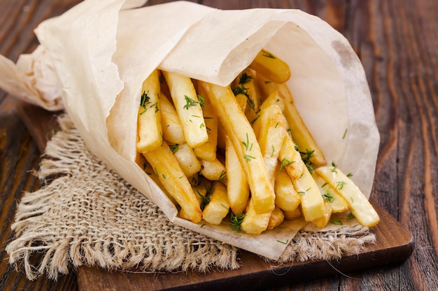 French fries with dill on wooden background