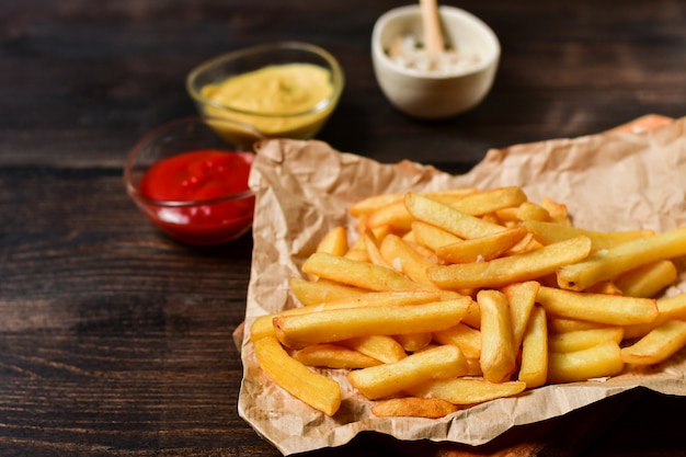 Patate fritte con ketchup, senape e sale. pranzo fast food su un tavolo di legno. menu del pranzo di lavoro, consegna fast food