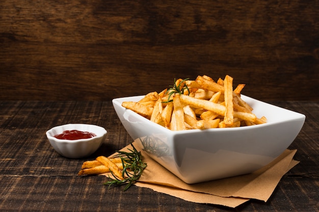 Patate fritte con ketchup sulla tavola di legno