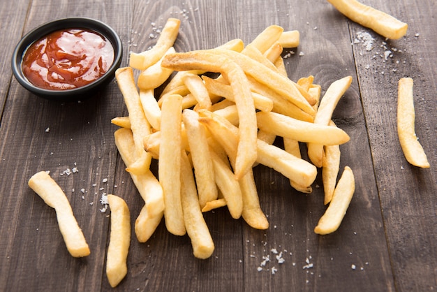 French fries with ketchup on wooden background