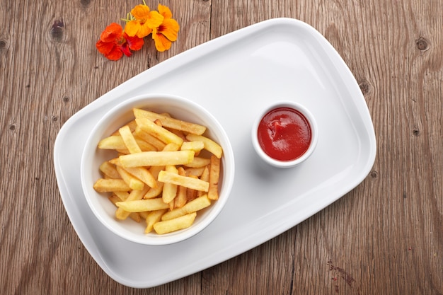 Patate fritte con salsa su un piatto bianco