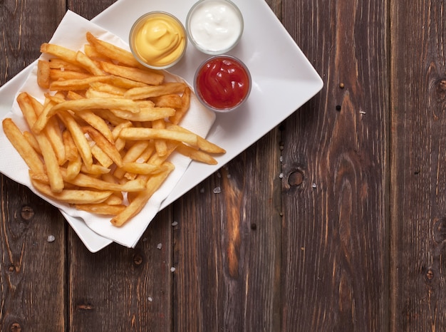 Patate fritte con salsa sulla tavola di legno.