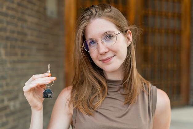 french girl with glasses holding home keys at outdoors smiling a lot