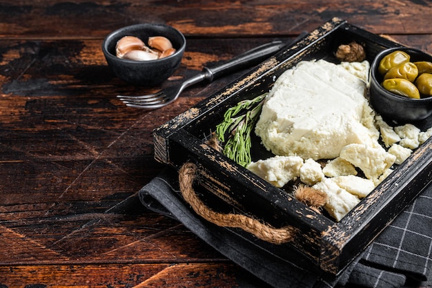 French Goat soft cheese in a tray with olives and rosemary. Wooden background. Top view. Copy space.