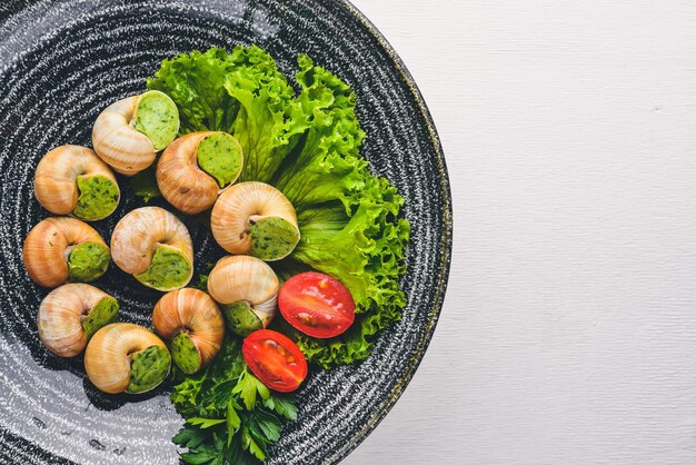 French and Italian cuisine Baked snails On a wooden background Top view Free space