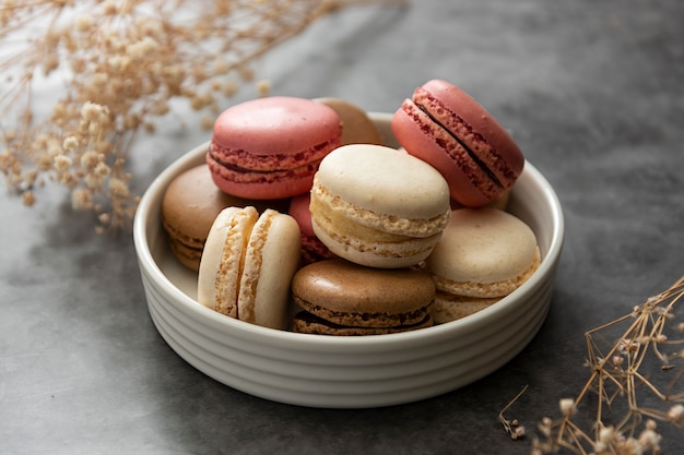 French macaron cakes in a plate close up. Cream, brown, pink, macarons with copy space.