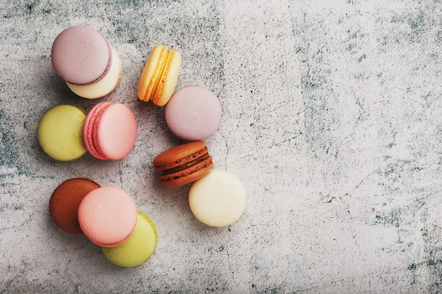 French macaroni cookies of different colors are on the gray table. Still life of confectionery.