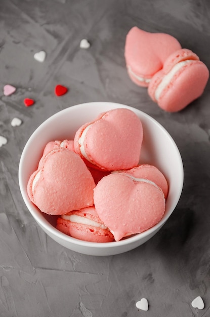 French macarons shaped of pink hearts in a white bowl for Valentine's Day copy space