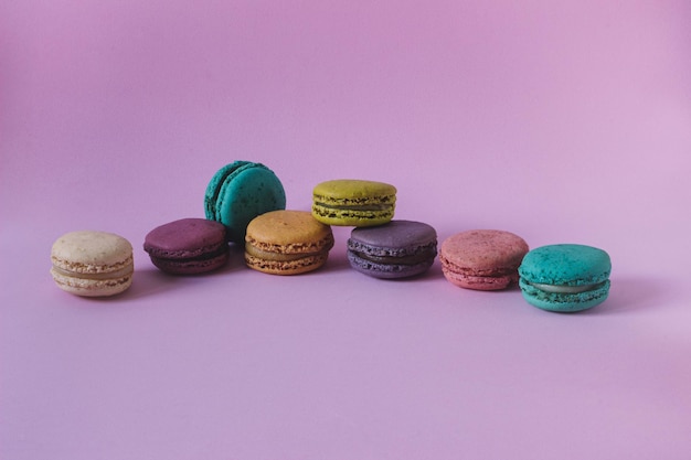 French macaroons of assorted colors in a row isolated on a pink background. copy space