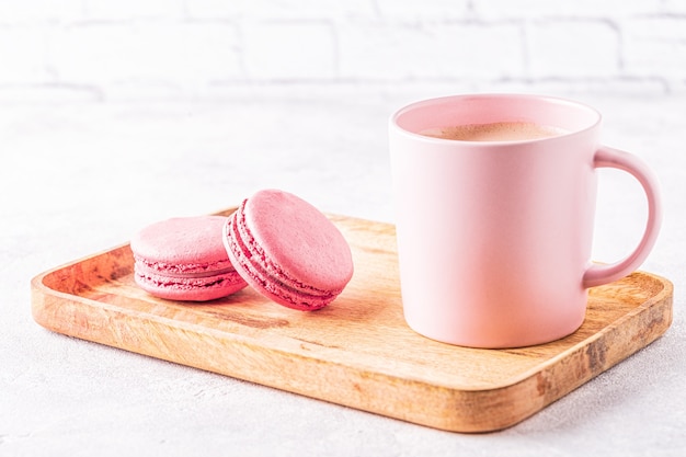 French macaroons and cup of coffee on a wooden tray.