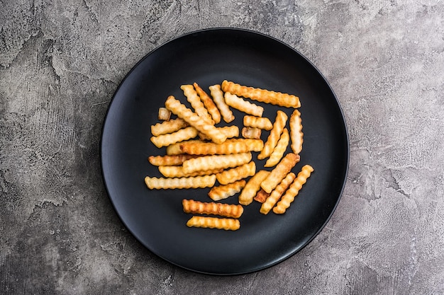 French potatoes on dark plate top view