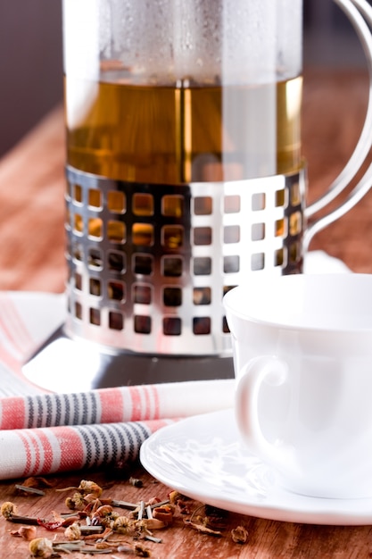 French press with herbal tea and cup closeup on wooden table