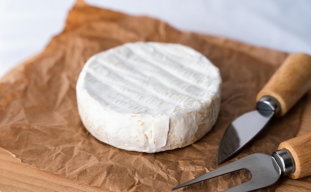 Foto formaggio morbido francese con muffa bianca camembert e coltelli per tagliare il formaggio sul tavolo della cucina closeup focus selettivo