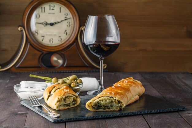 French stuffed bread with olives and glass of red wine on table