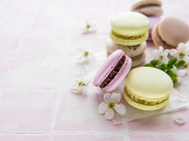 French sweet macaroons colorful variety on a pink tile surface with spring blossom