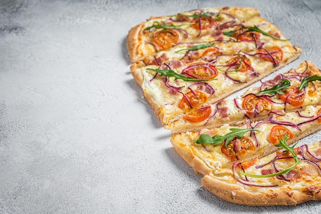 French tarte flambee with cream cheese bacon tomato and onions Flammkuchen from Alsace region White background Top view Copy space