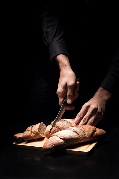 French taste. Close up of male chefs hands chopping the baguette