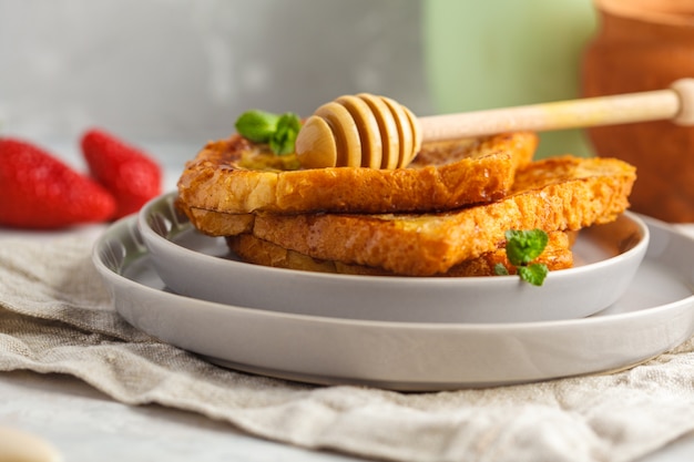 French toast with honey in plates. Gray background