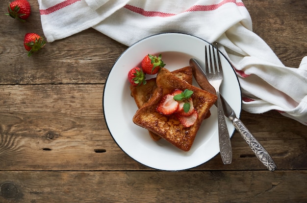 French toasts with honey and strawberries on a plate