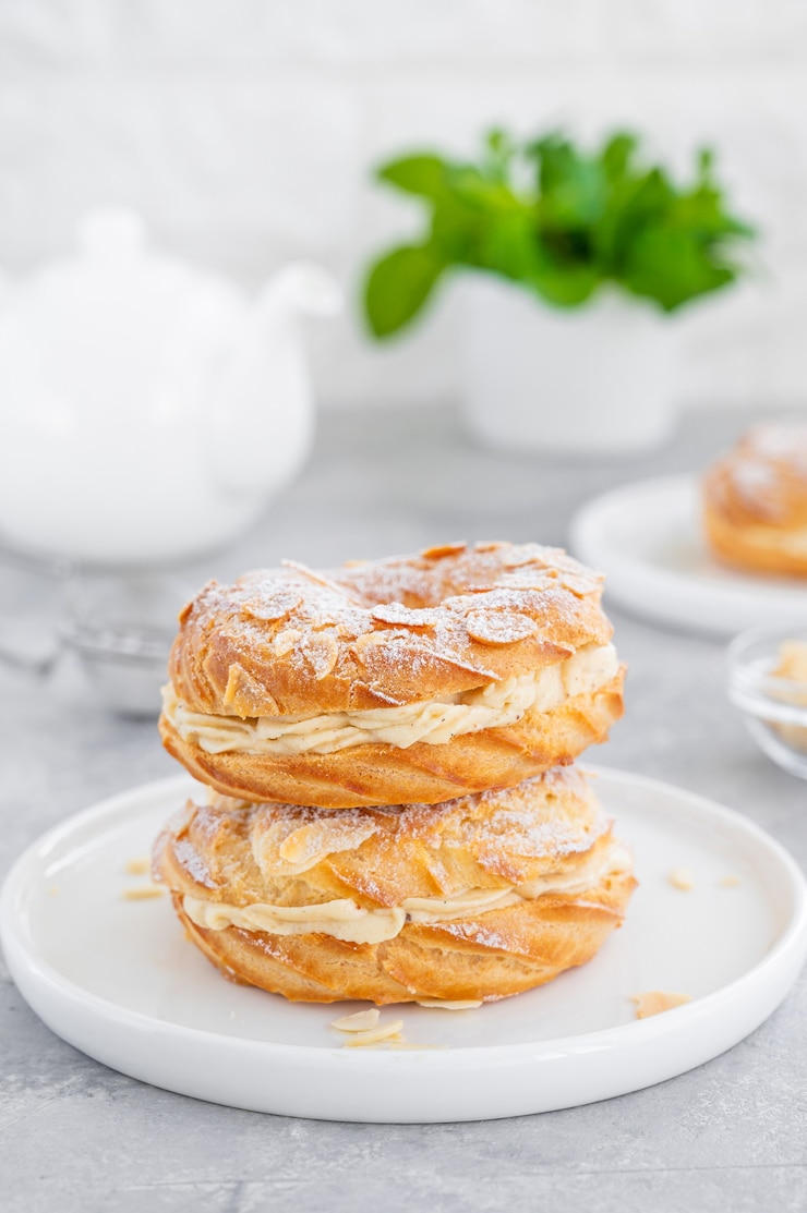 Photo french traditional cake paris brest with praline cream, powdered sugar and almond petals on a plate