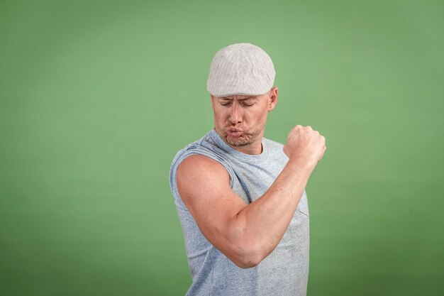 Frenchman with gray cap and gray shirt against green background person