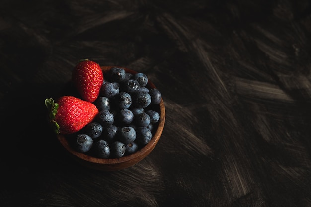 Photo fresas y arandanos en bowl de madera