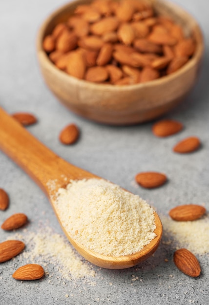 Fresh almond flour in a wooden spoon and almonds