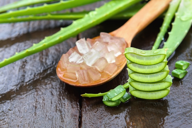 Fresh aloe vera gel in spoon on wood