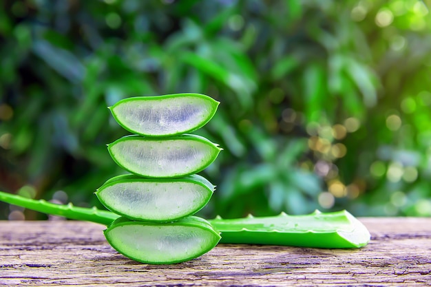 Fresh aloe vera leaves and slices on wooden table.