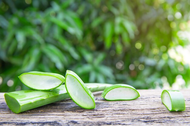 Fresh aloe vera leaves and slices on wooden table.