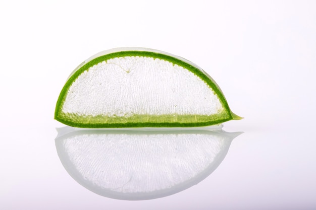 Fresh aloe vera slices on white surface with reflection