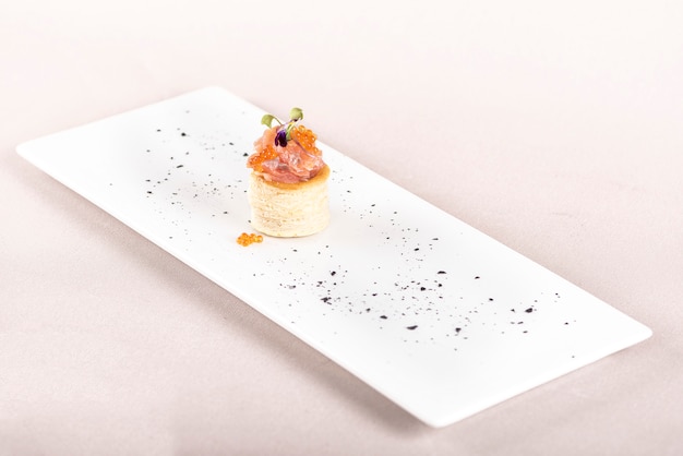 Fresh appetizer with smoked salmon and caviar,  on pastry, eatable purple flower 