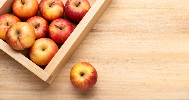 Fresh apple background with copy space. Red apples in crate on wooden table