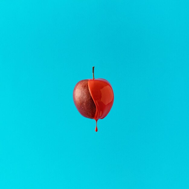 Свежее яблоко, погруженное в красную боль на синем фоне Минимальная творческая концепция