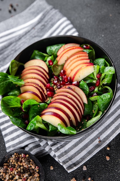 fresh apple salad, green mix lettuce, pomegranate grain healthy meal food snack on the table