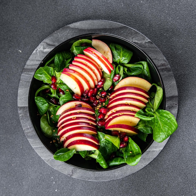 fresh apple salad, green mix lettuce, pomegranate grain healthy meal food snack on the table