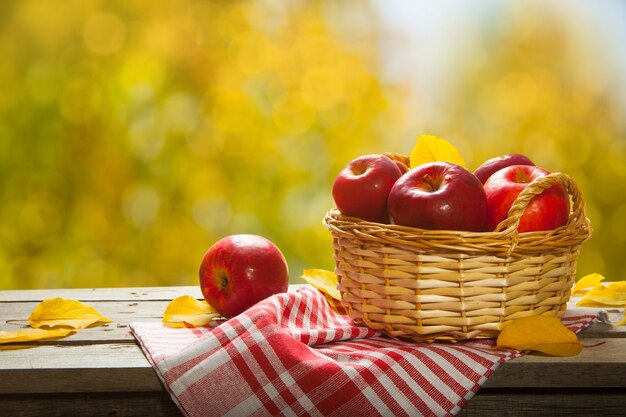 Fresh apples in the basket. On wooden background. Free space for text