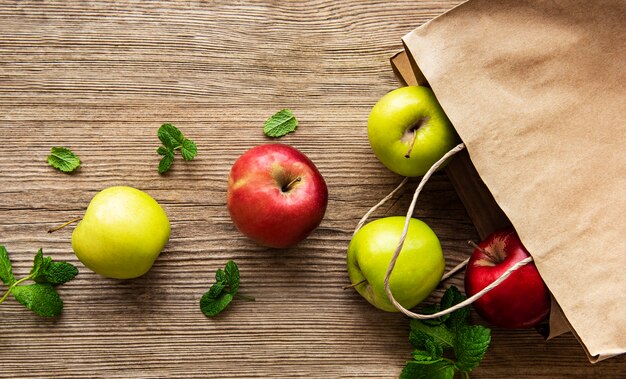 Fresh apples in a paper bag on a wooden table