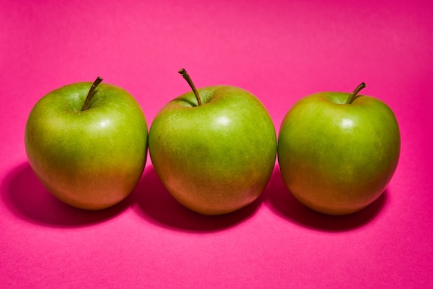 Fresh apples on pink background