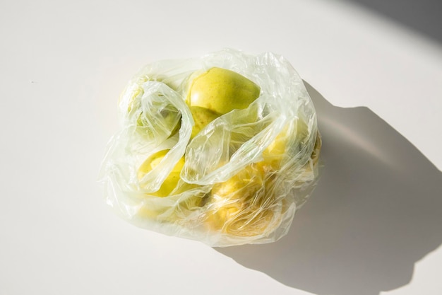 Fresh apples in a plastic bag on a white table Top view flat lay