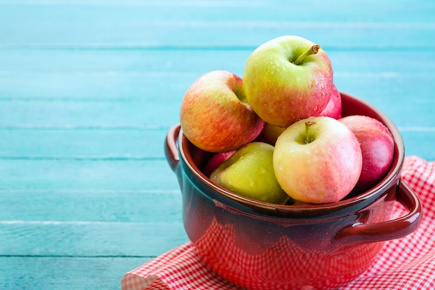 Photo fresh apples in a red pan on a blue wooden background