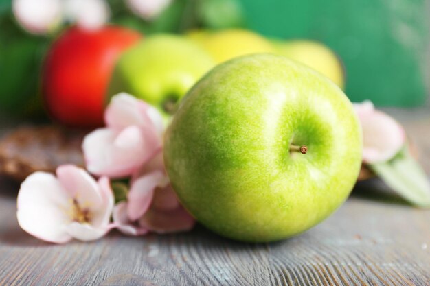 Fresh apples with apple blossom on wooden table