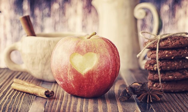 木の板に新鮮なリンゴ。赤いリンゴの収穫。テーブルの上の果物とシナモン。