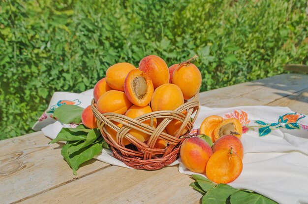 Свежие абрикосы в корзине на деревянном столе