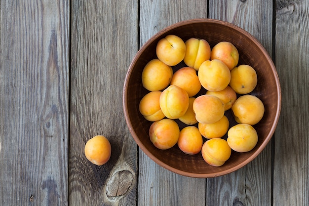 Fresh apricots in a bowl on a wooden table. Rustic style