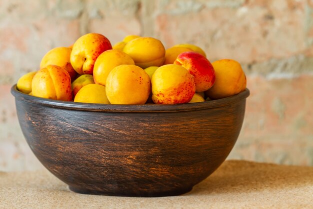 Fresh apricots on a metal plate on a brick background. Closeup, selective focus