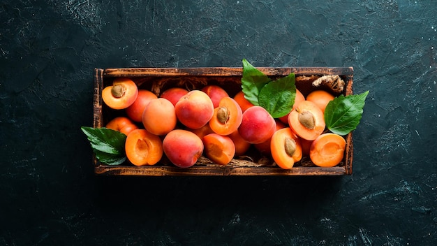 Fresh apricots with green leaves in a box Rustic style Top view Free space for your text