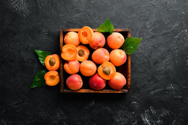 Fresh apricots with green leaves in a box Rustic style Top view Free space for your text