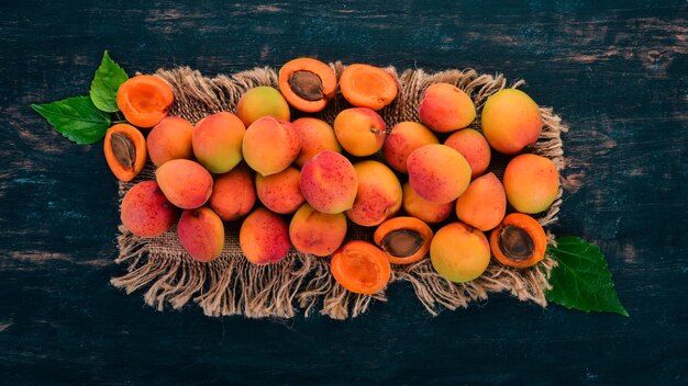 Fresh apricots with leaves On a black wooden background Top view Free space for your text